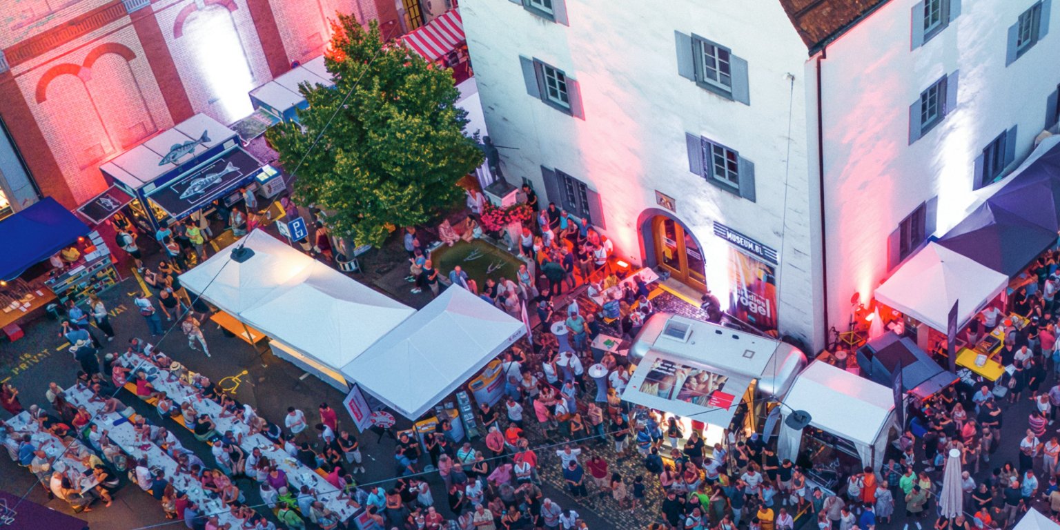 Eine belebte Strasse bei Nacht mit Marktständen und vielen Menschen für BLKB bei uns in Liestal.