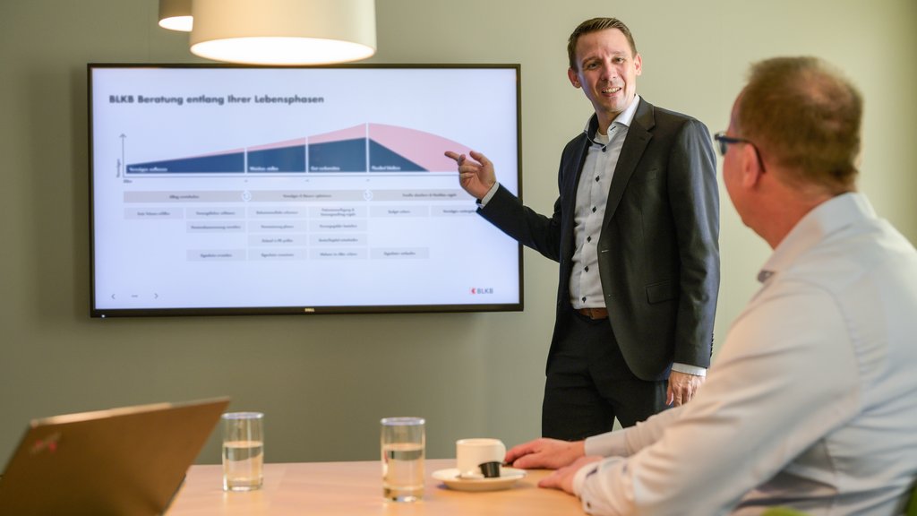 Mann erklärt eine Präsentation an einem Bildschirm bei der BLKB in einem Meeting.