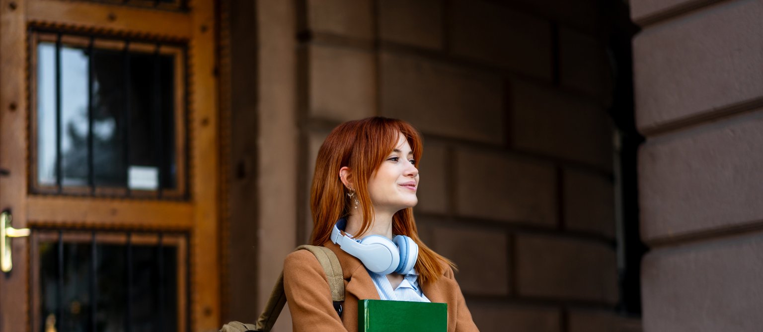 Eine junge Frau mit Rucksack und Buch.