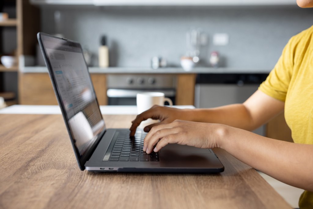Person, die an einem Laptop in einer modernen Küche tippt.