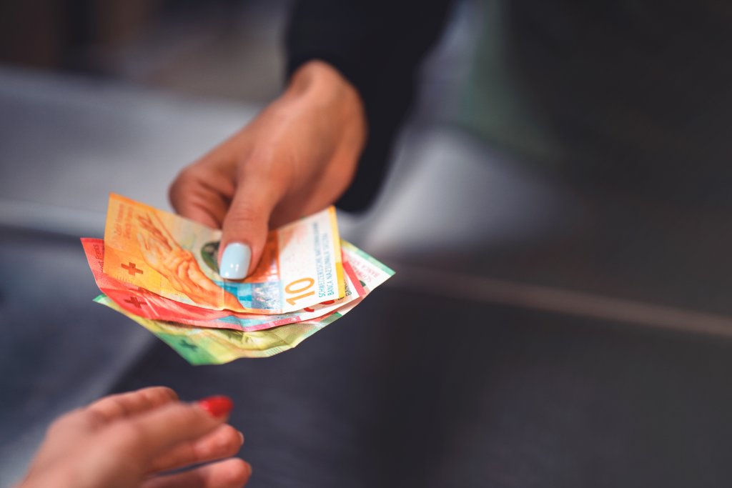 Hand einer Frau reicht Bargeld zum Bezahlen