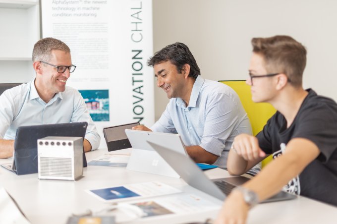 3 Männer von Alpha Diagnostics mit ihren Laptops in einem Meeting.
