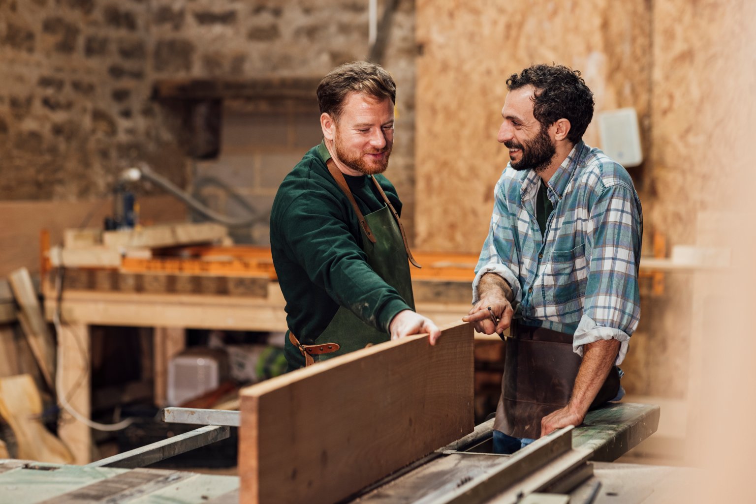Zwei Männer arbeiten in einer Werkstatt an Holzarbeiten.