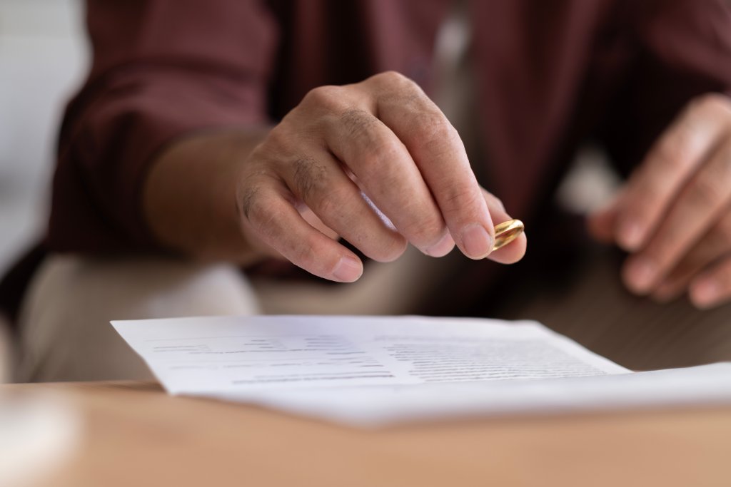Hand hält einen goldenen Schlüssel über einem Papierdokument.