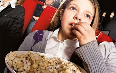 Ein kleines Mädchen isst Popcorn im Kino.