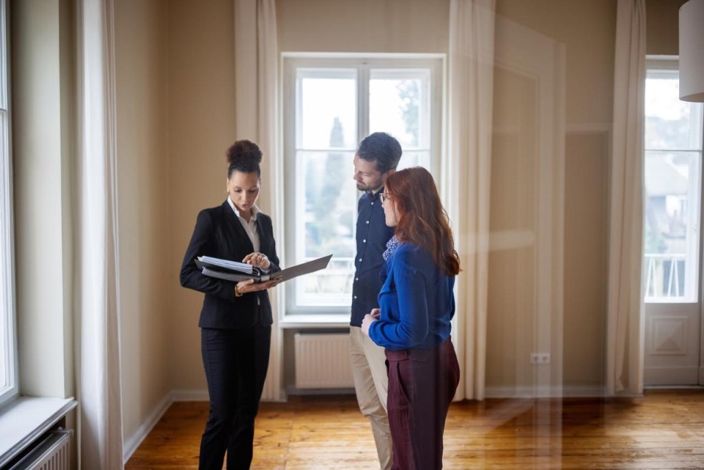Immobilienmaklerin zeigt Kunden eine Wohnung. Sie stehen in einer leeren neuen Wohnung.
