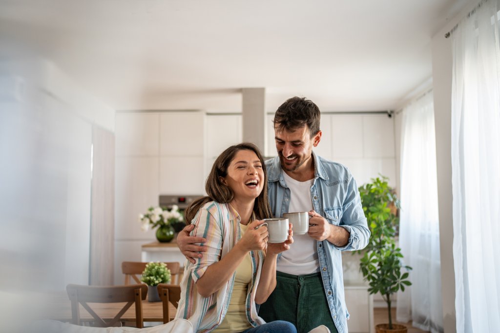 Junges Paar trinkt morgens Kaffee und geniesst das Wochenende in seiner neuen Wohnung.