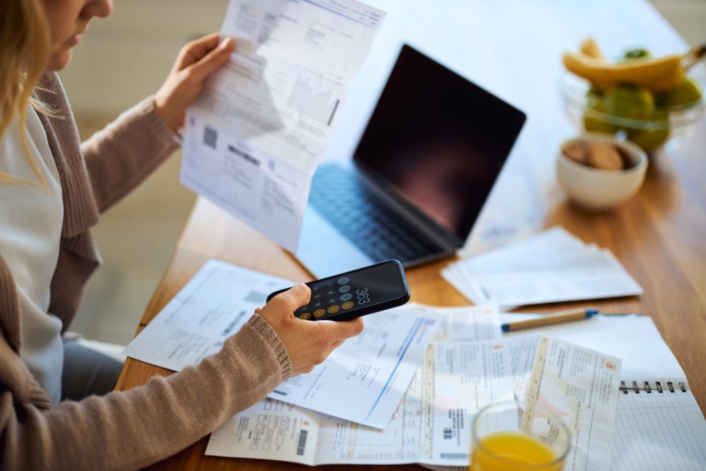 Eine Frau verwaltet ihre Finanzen am Schreibtisch mit Laptop und Dokumenten.