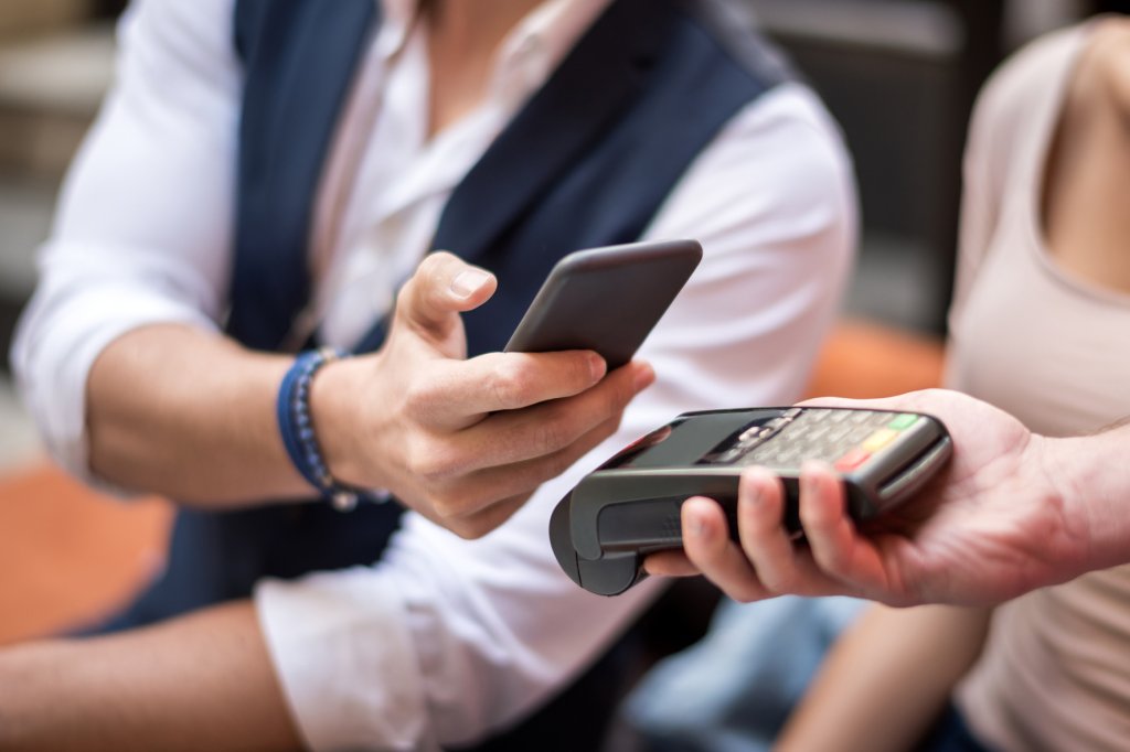 Der Kunde hält sein Mobiltelefon für eine kontaktlose Zahlungstransaktion über das Kreditkartenlesegerät.