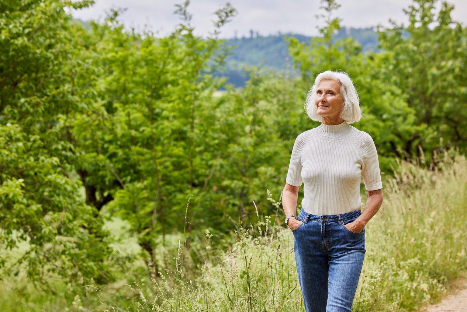 Frau geht entspannt durch die Natur und geniesst die frische Luft
