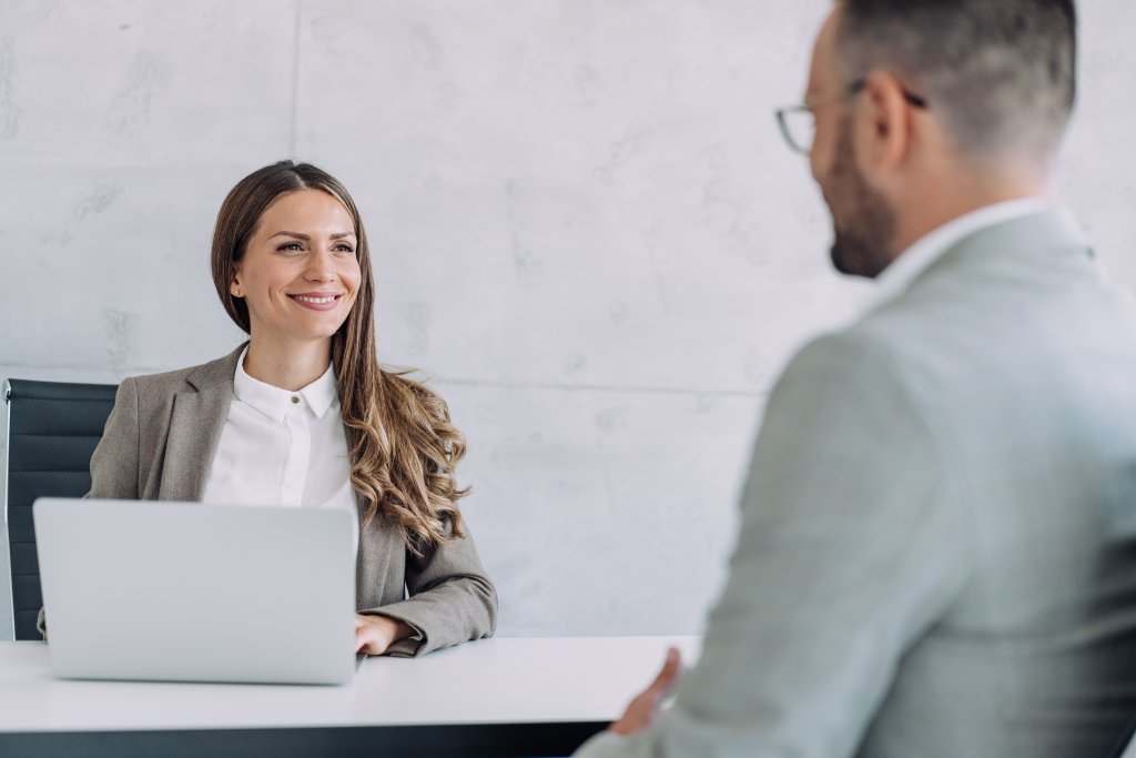 Eine Geschäftsfrau lächelt während eines Treffens mit einem Kollegen in einem modernen Büro.