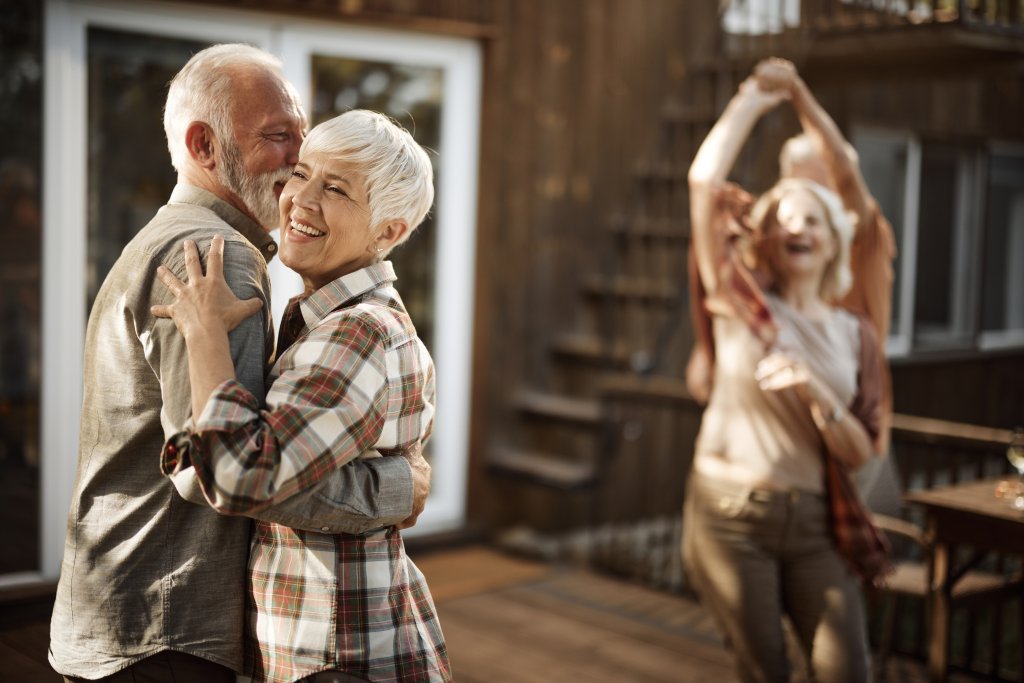 Eine fröhliche Gruppe tanzt und feiert zusammen auf einer Terrasse bei Sonnenuntergang.