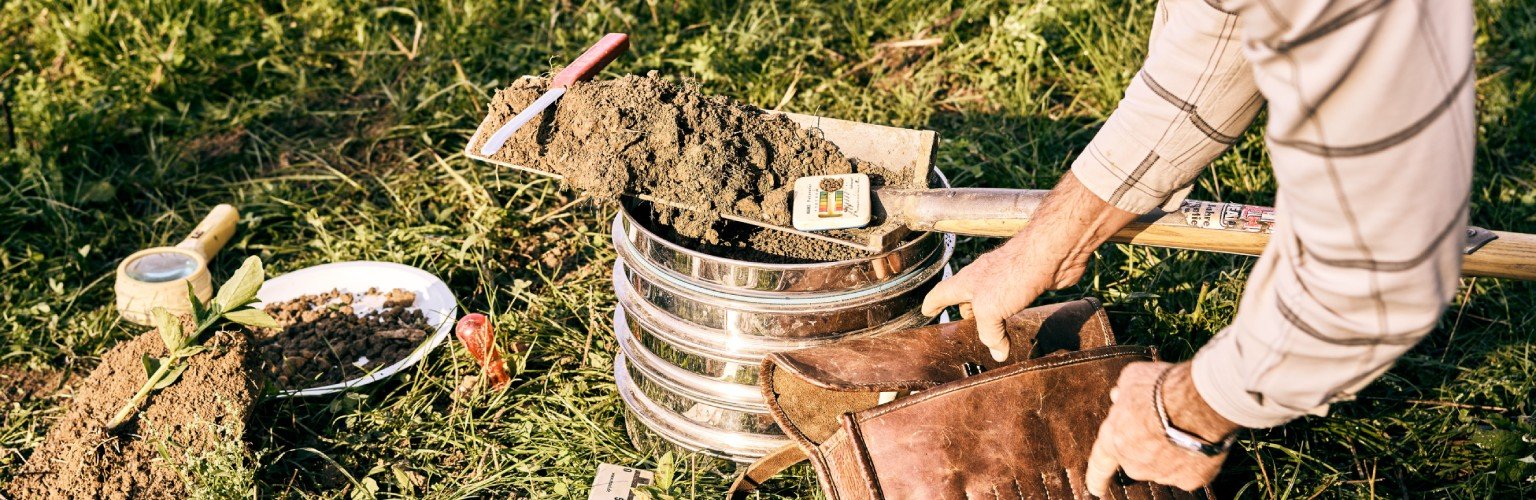 Ein Mann gräbt im Garten mit Werkzeugen und einer Blumentopf.