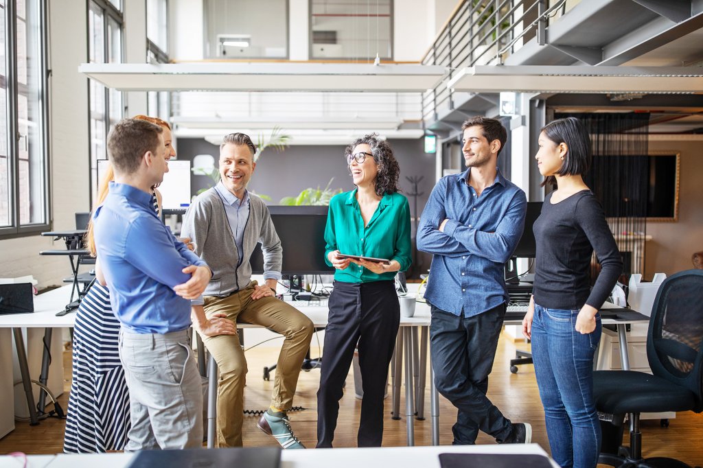 Geschäftsleute stehen in einem modernen Büro und führen eine Besprechung durch