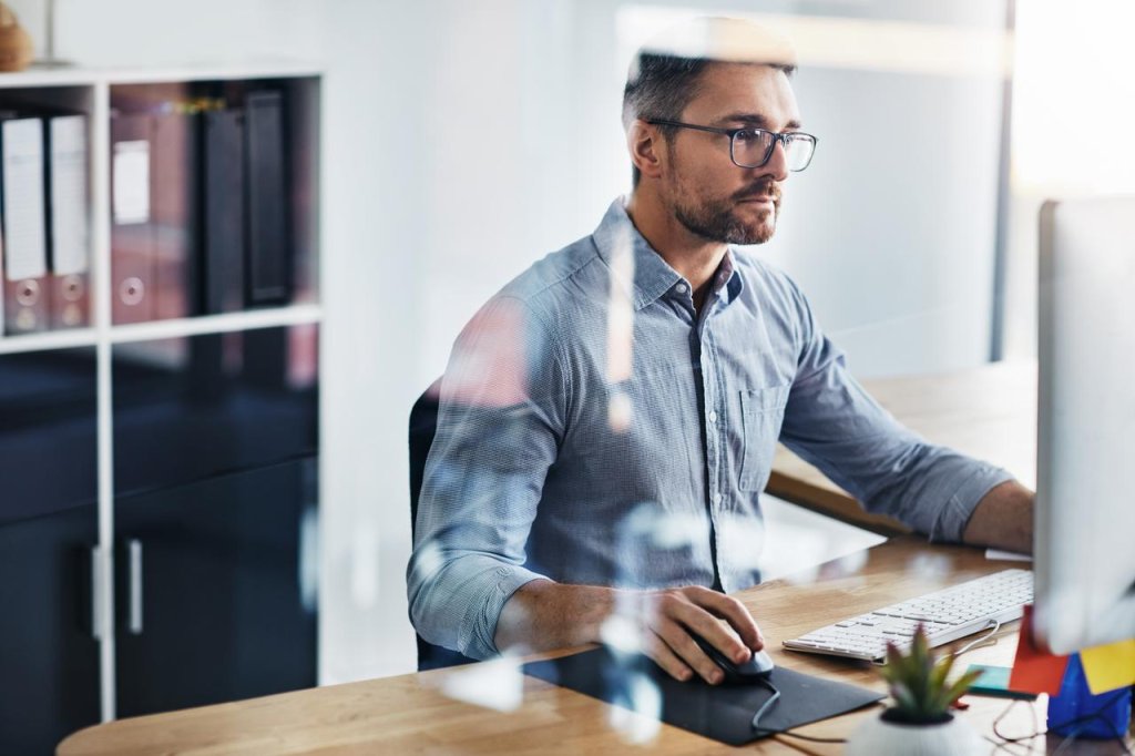 Mann arbeitet am Computer in einem modernen Büro der Basellandschaftlichen Kantonalbank (BLKB).