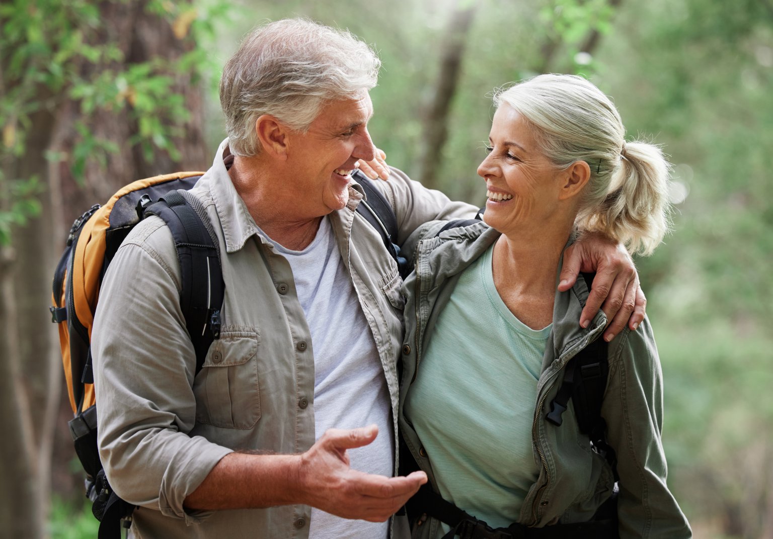 Ein Mann und eine Frau lachen sich beim Wandern im Wald an.