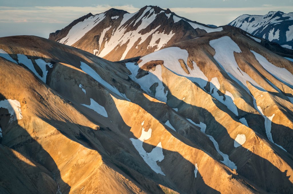 Berglandschaft mit schneebedeckten Gipfeln und rauem Terrain unter einem klaren Himmel.