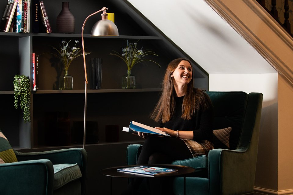 Customer reading and smiling in quiet area of the lounge at Cornwall Buildings