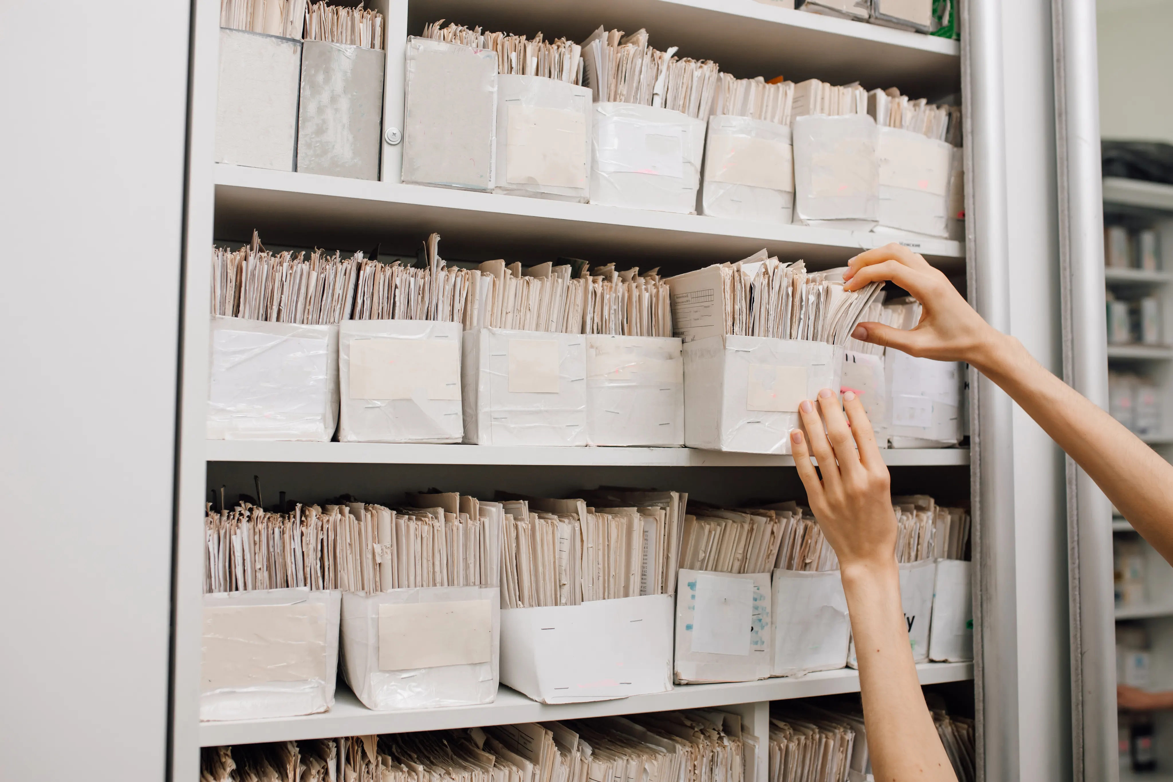 Hands of woman working with records stored in filing cabinet