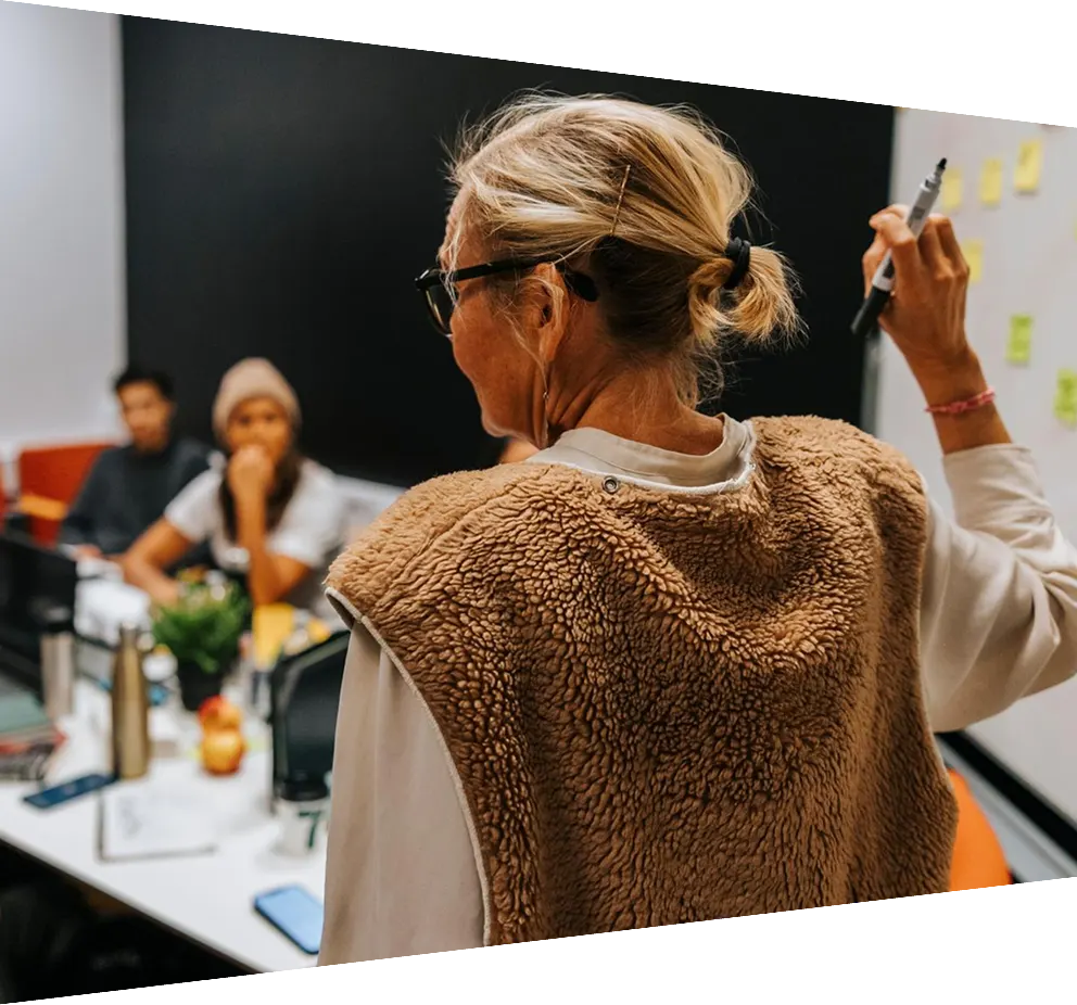 Rear view of female teacher teaching multiracial students in college classroom 