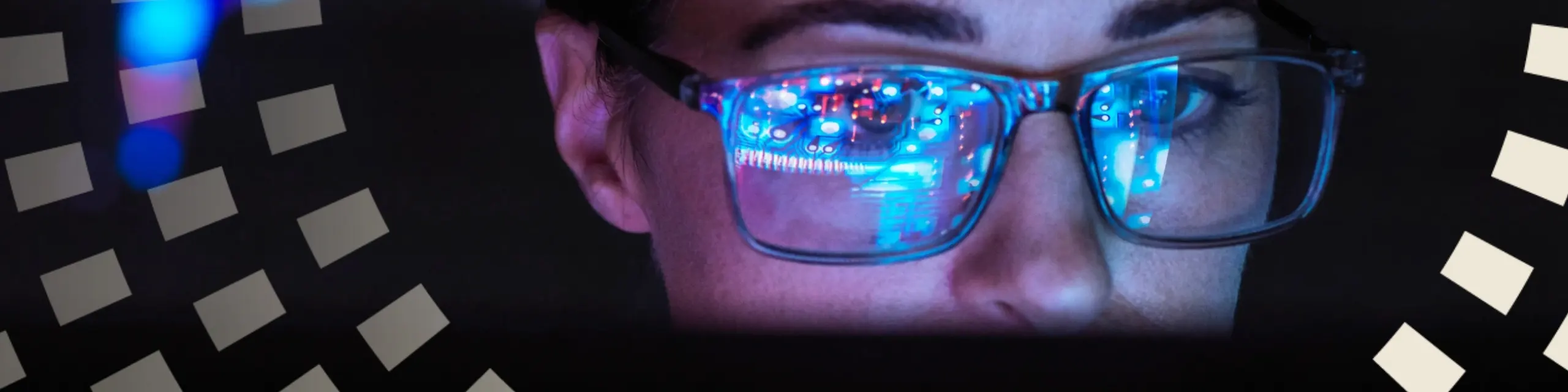 A woman looking in front of her desktop with data reflecting on her eyeglass