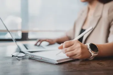 woman looking at laptop and taking notes