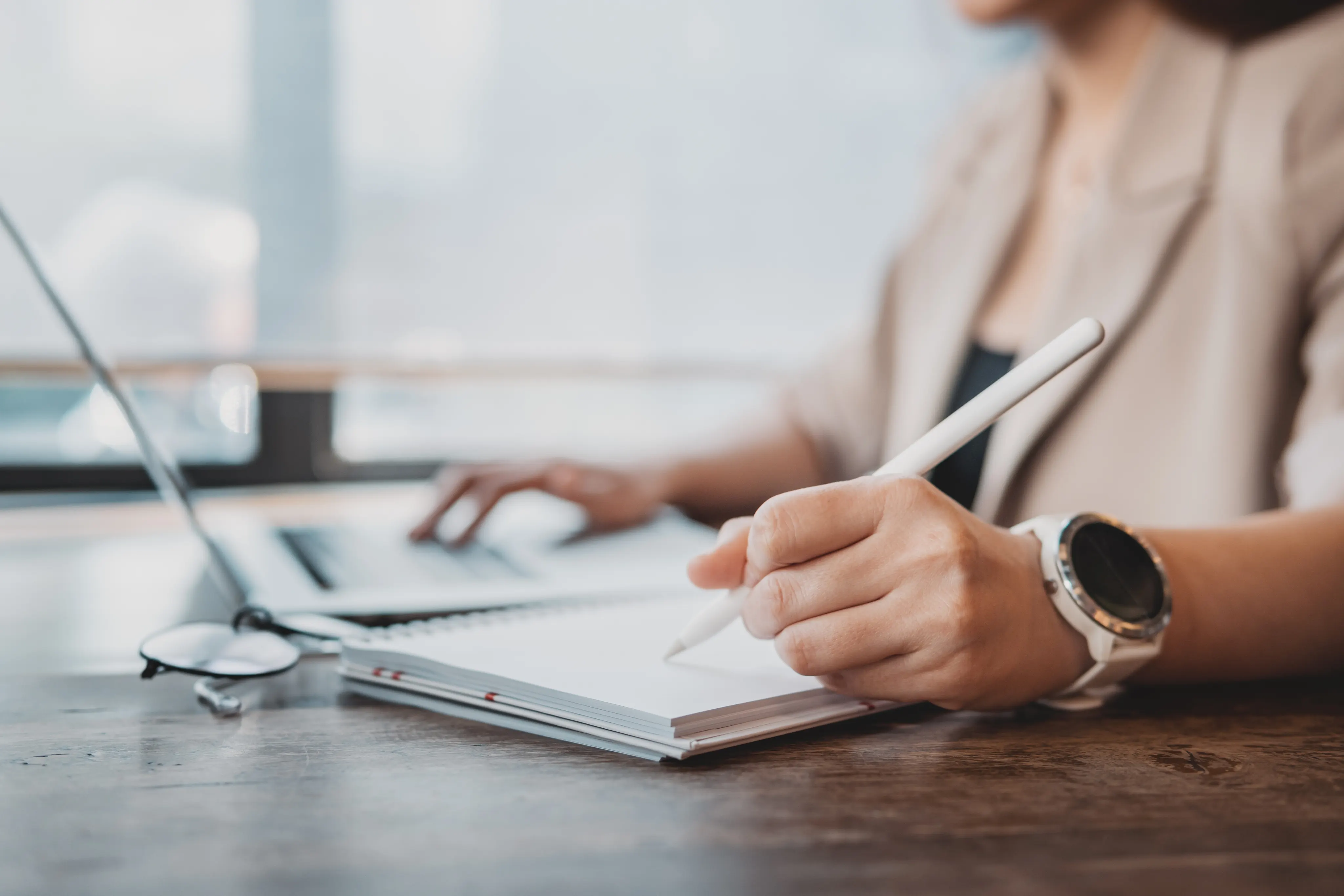 woman looking at laptop and taking notes