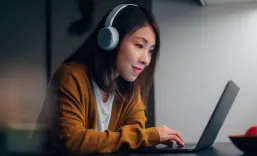 Young Asian woman with headphone, studying online with laptop at home during the night