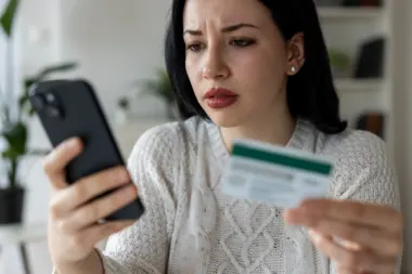 Woman Looking at Smartphone While Holding Credit Card