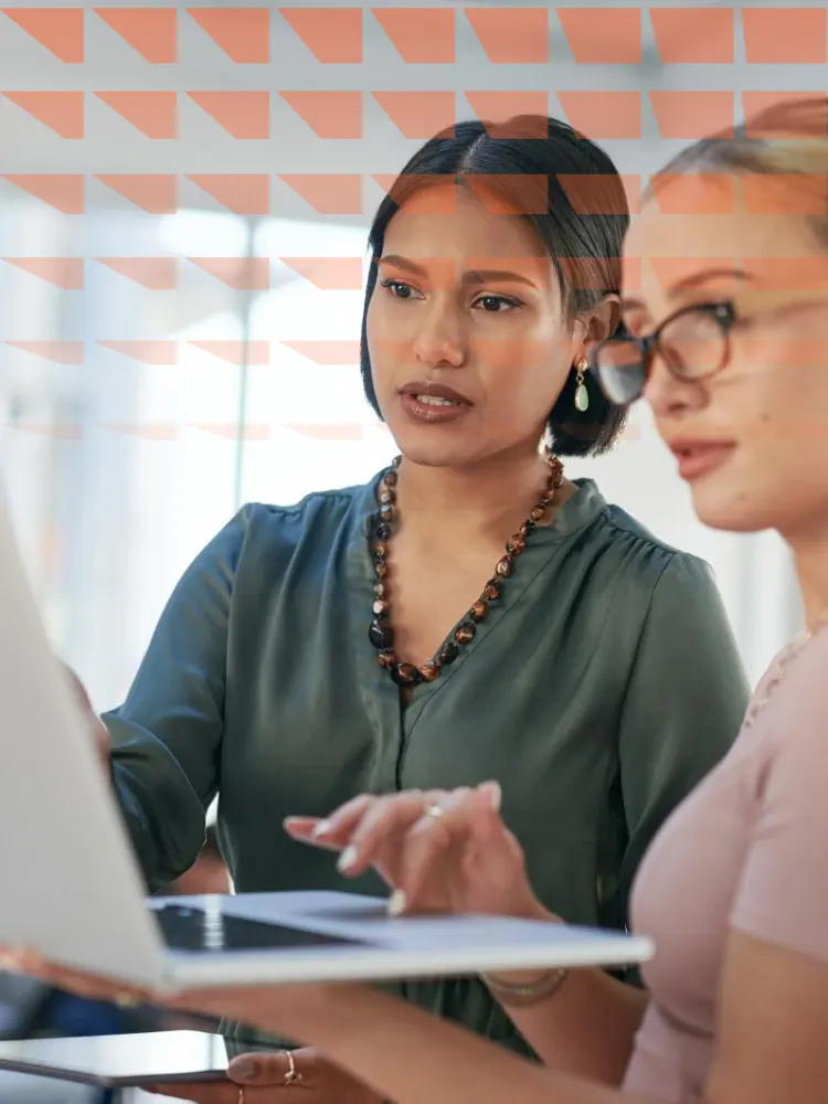 Two young businesswomen using a laptop during a meeting in a modern office