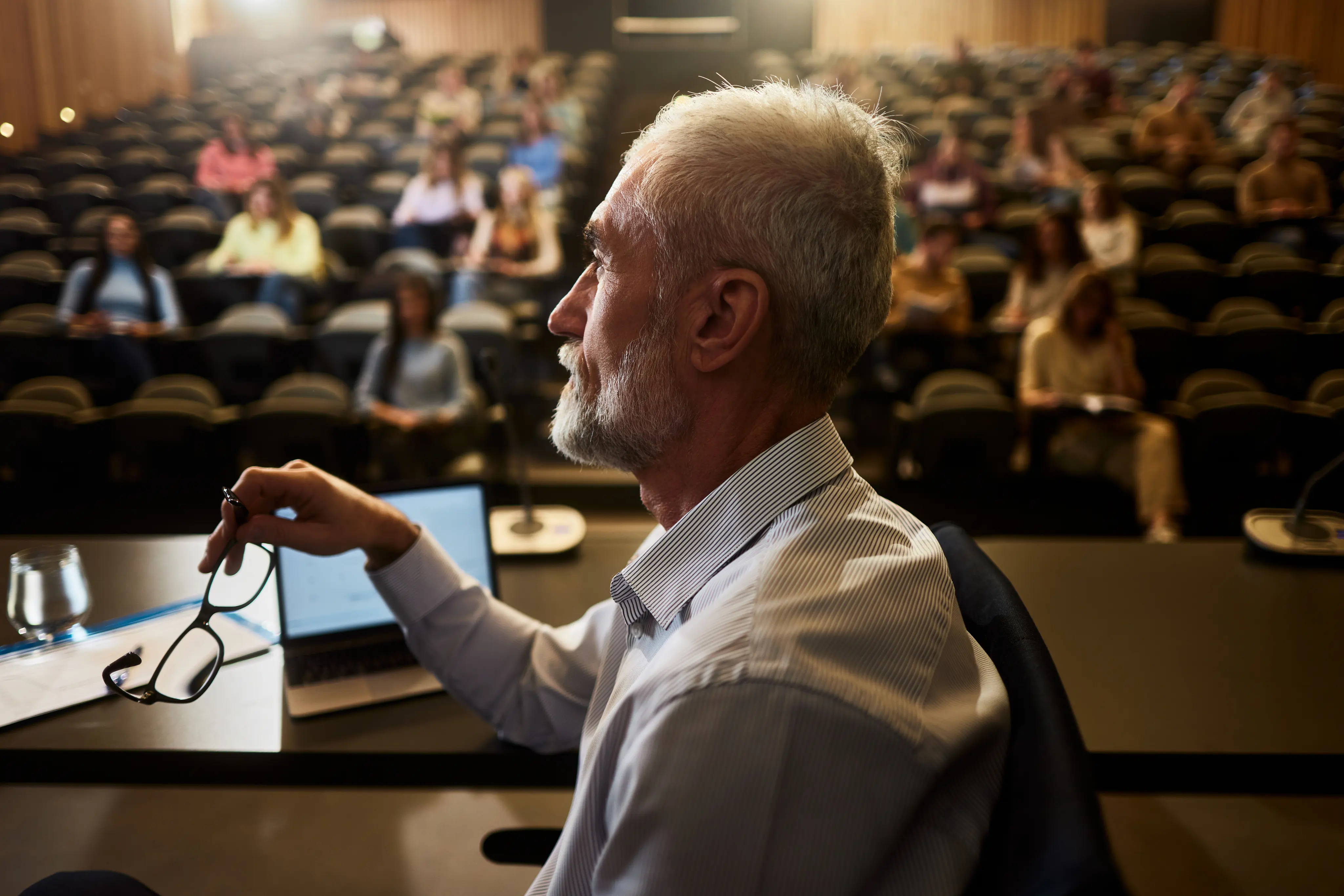 A man standing in front of a group of peers and presenting.