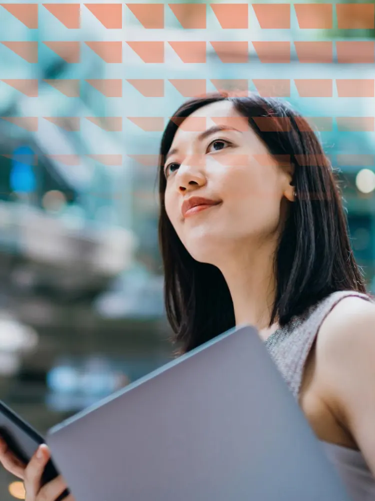 Modern young Asian businesswoman carrying smartphone and laptop, commuting to work