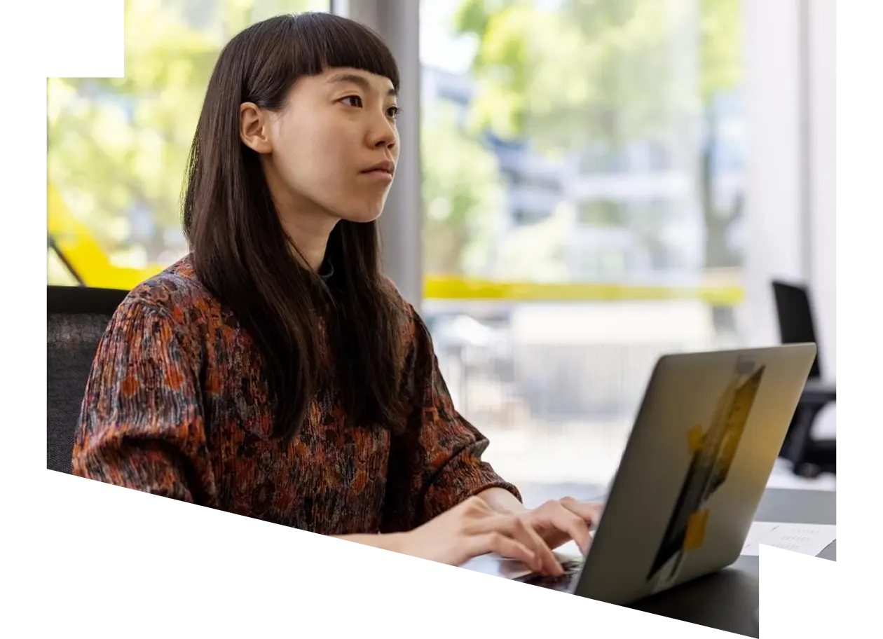 Young female engineer using laptop and looking at desktop monitor