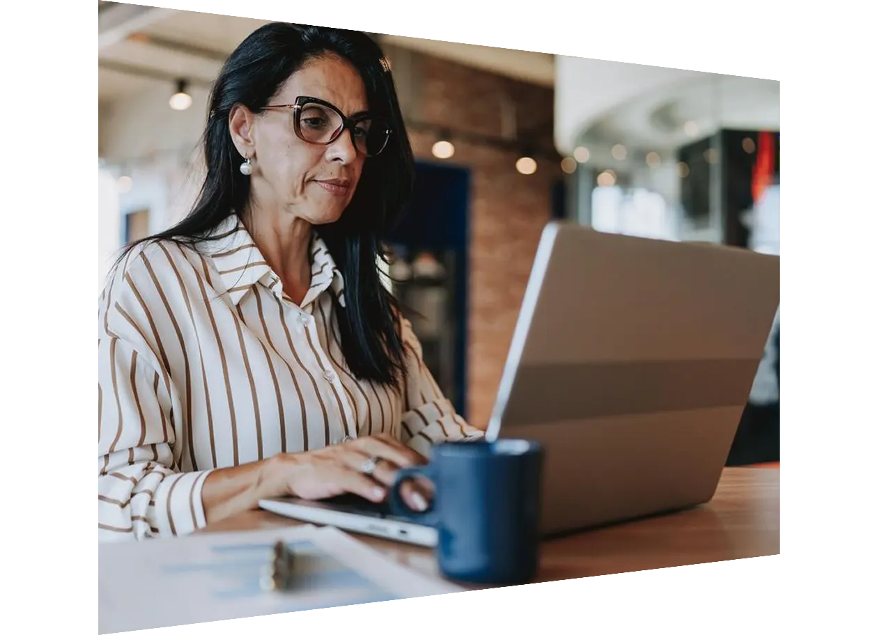 A man wearing glasses is focused on his laptop screen.