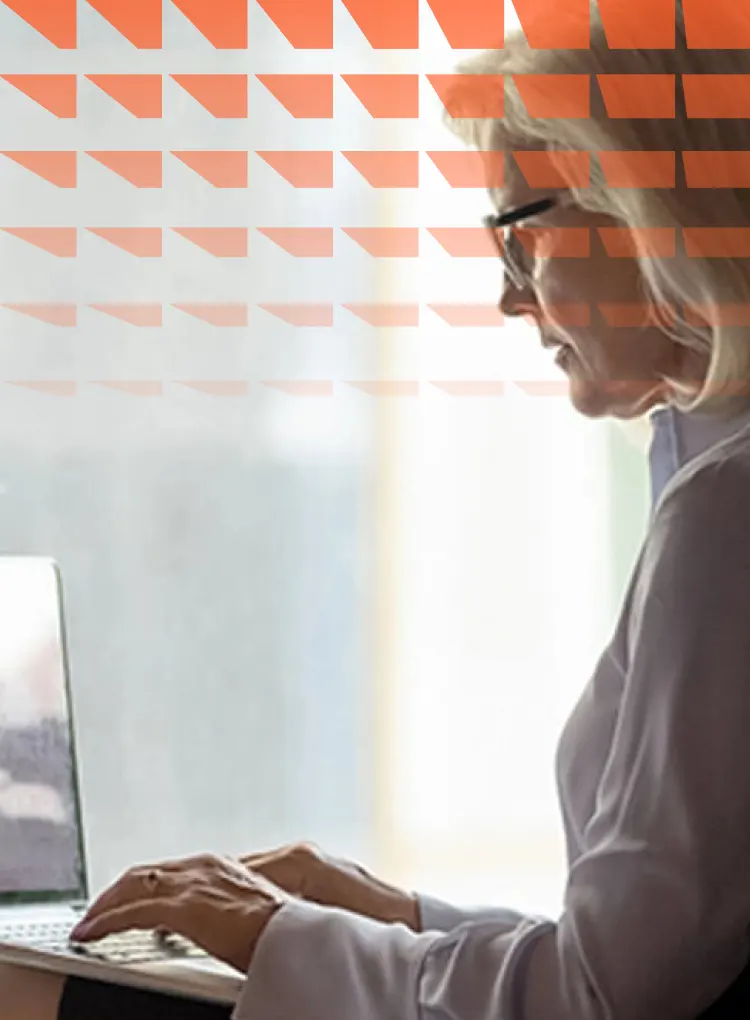 Woman sitting next to window working on laptop