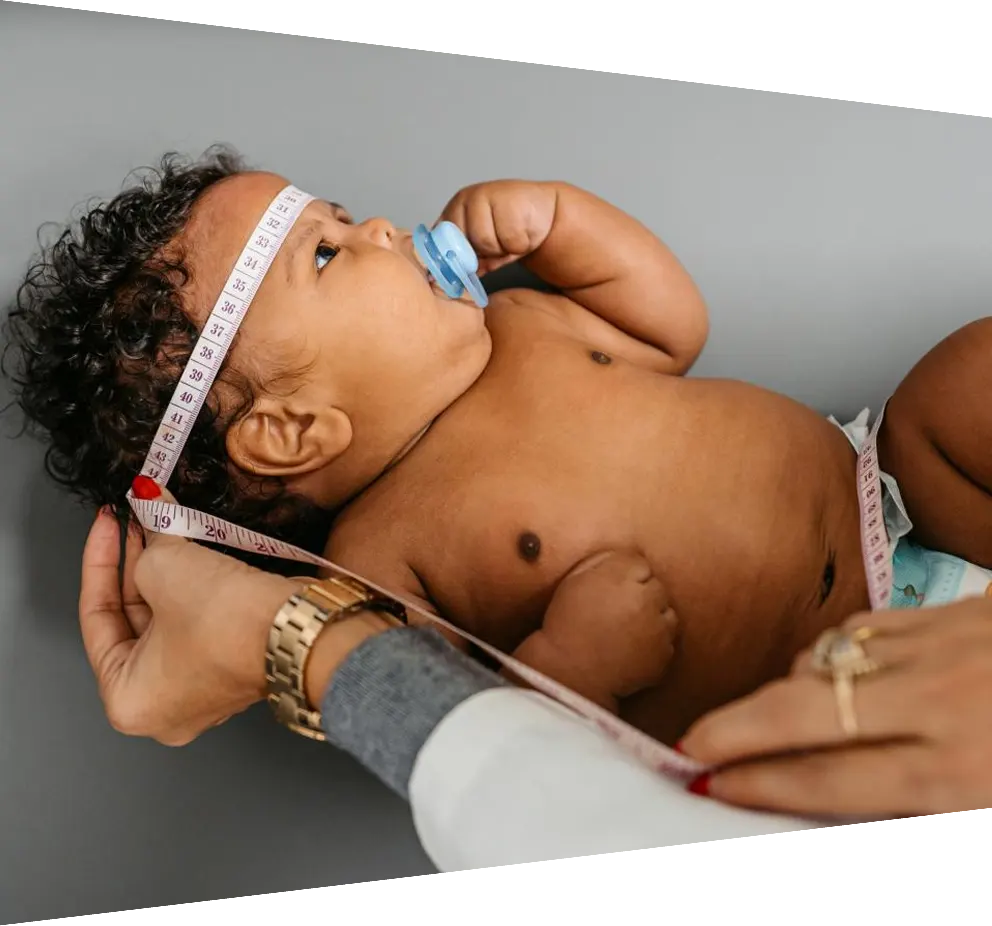 Young female pediatrician measuring newborn baby boy's head