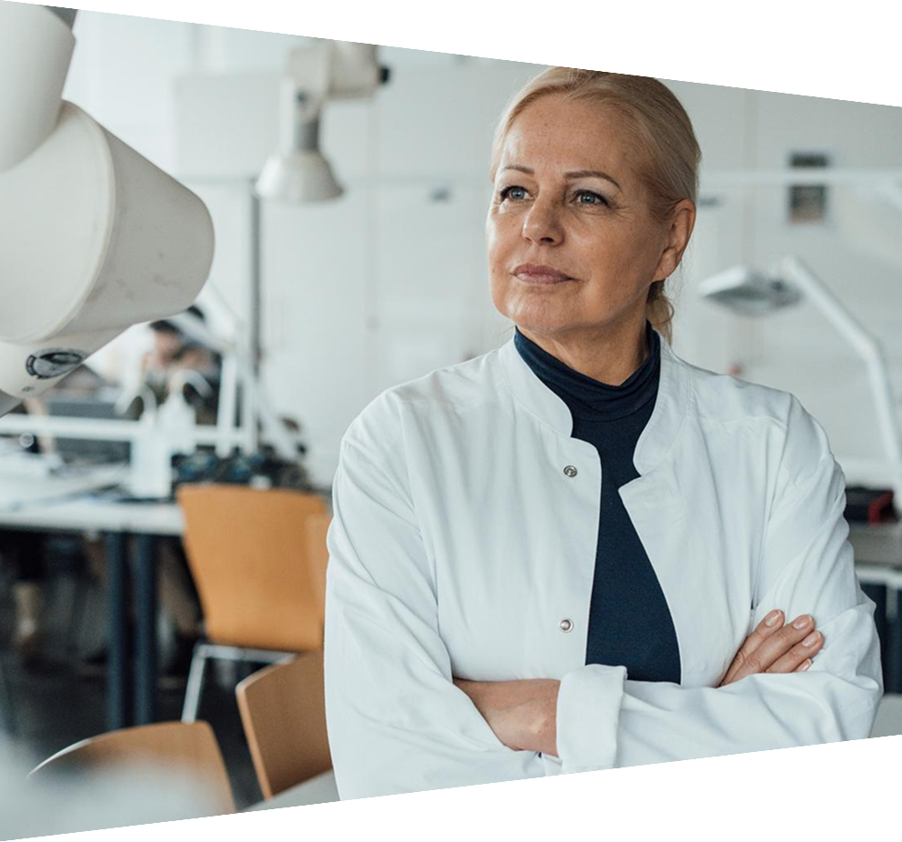 Thoughtful senior scientist standing with arms crossed in laboratory