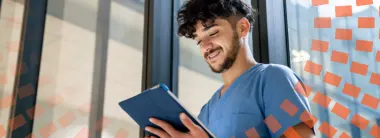 Enfermero joven sonriendo y mirando hacia abajo una tableta