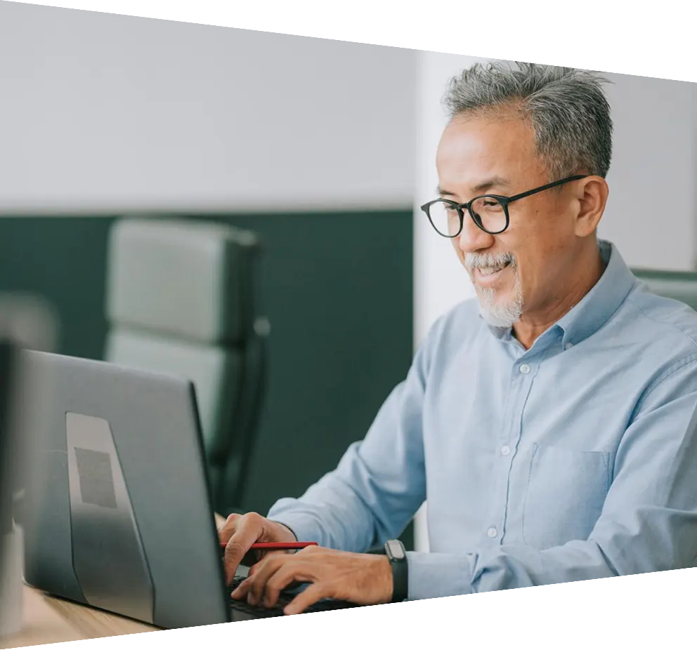 Senior Asian man with facial hair working on laptop in office