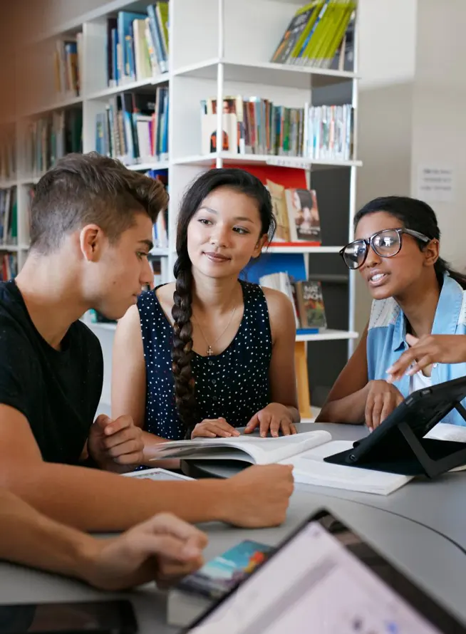 Students working in groups with tablets and laptop in library