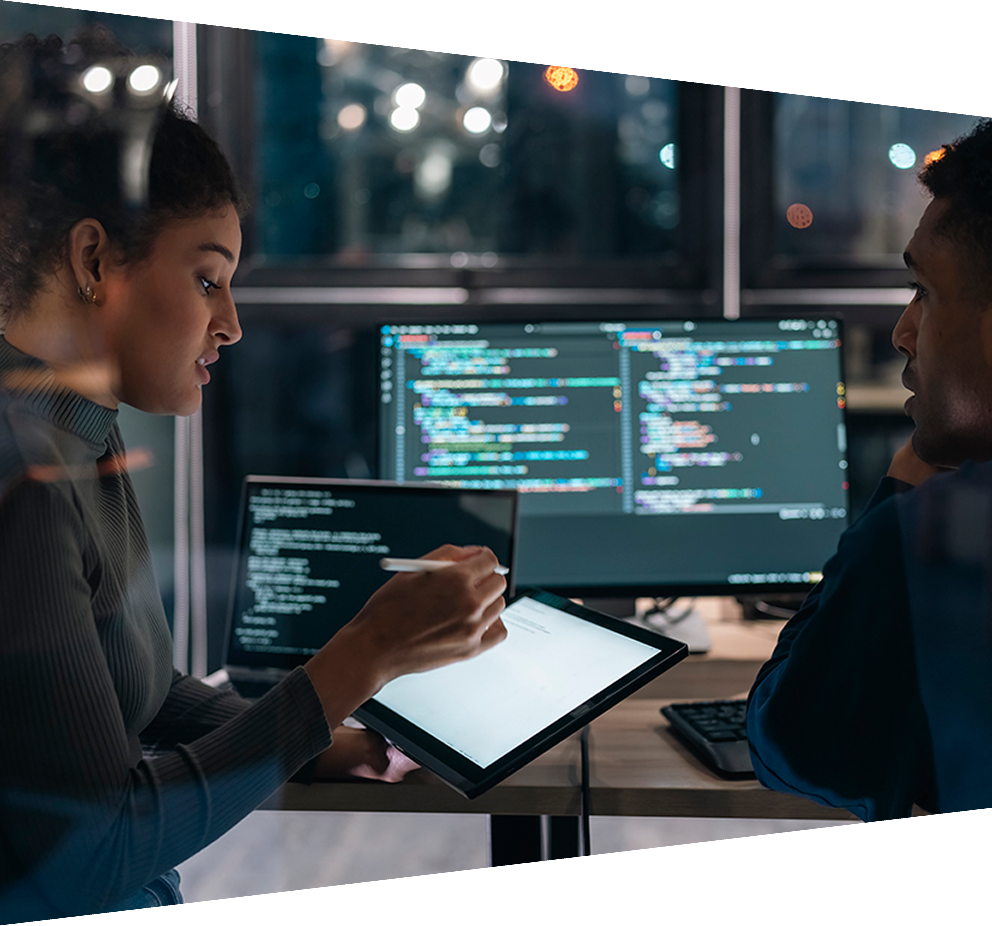 Two software developers collaborating on analysing code on a computer screen