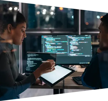 Two software developers collaborating on analysing code on a computer screen