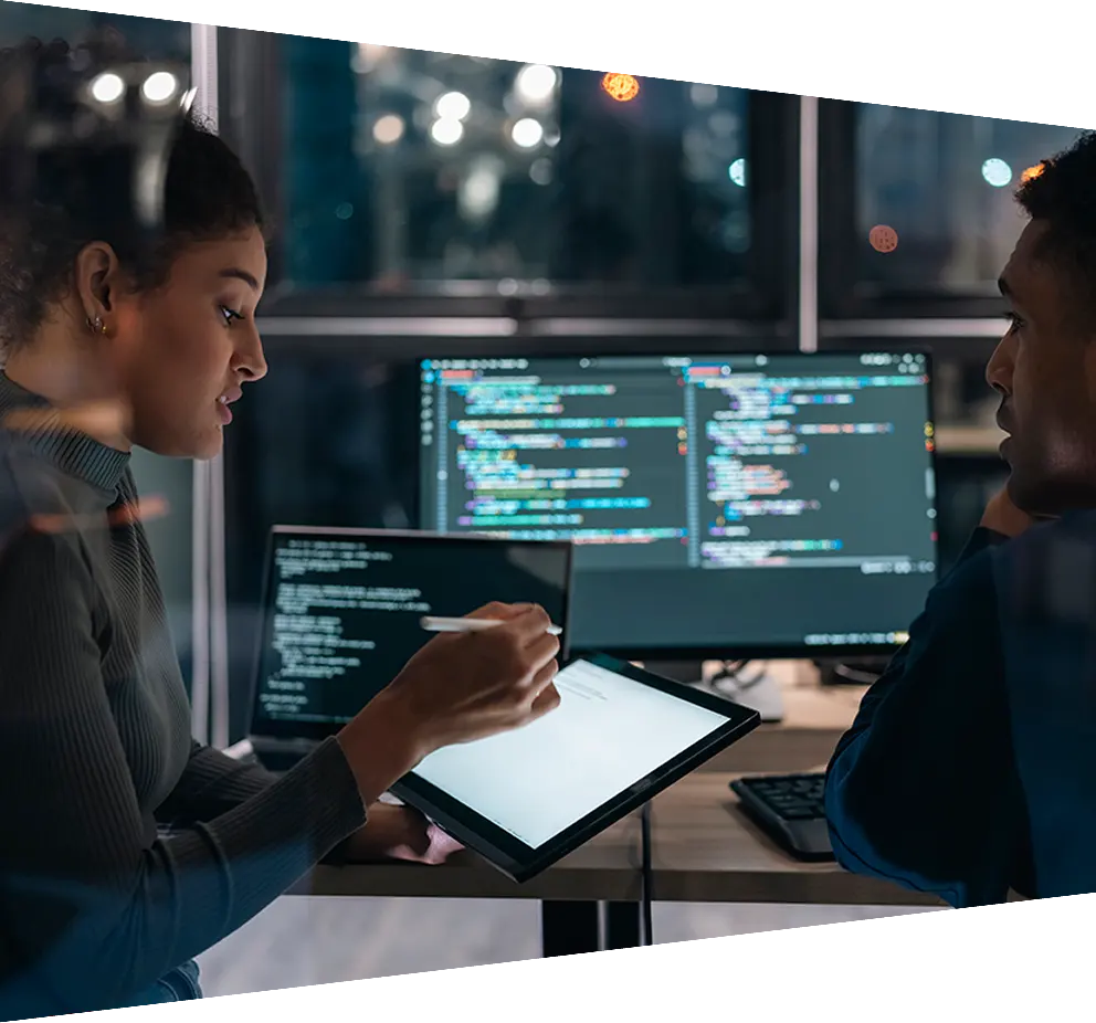 Two software developers collaborating on analysing code on a computer screen