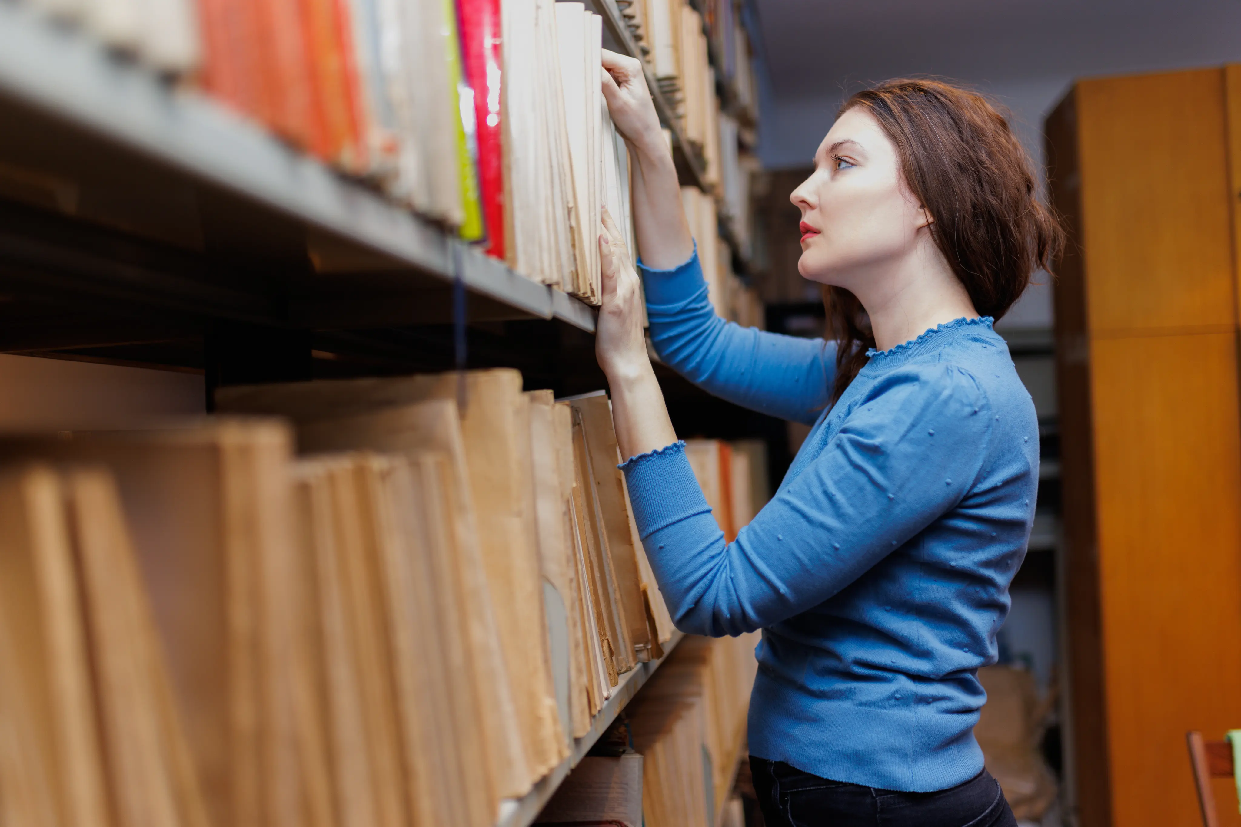 Woman researching in library stacks