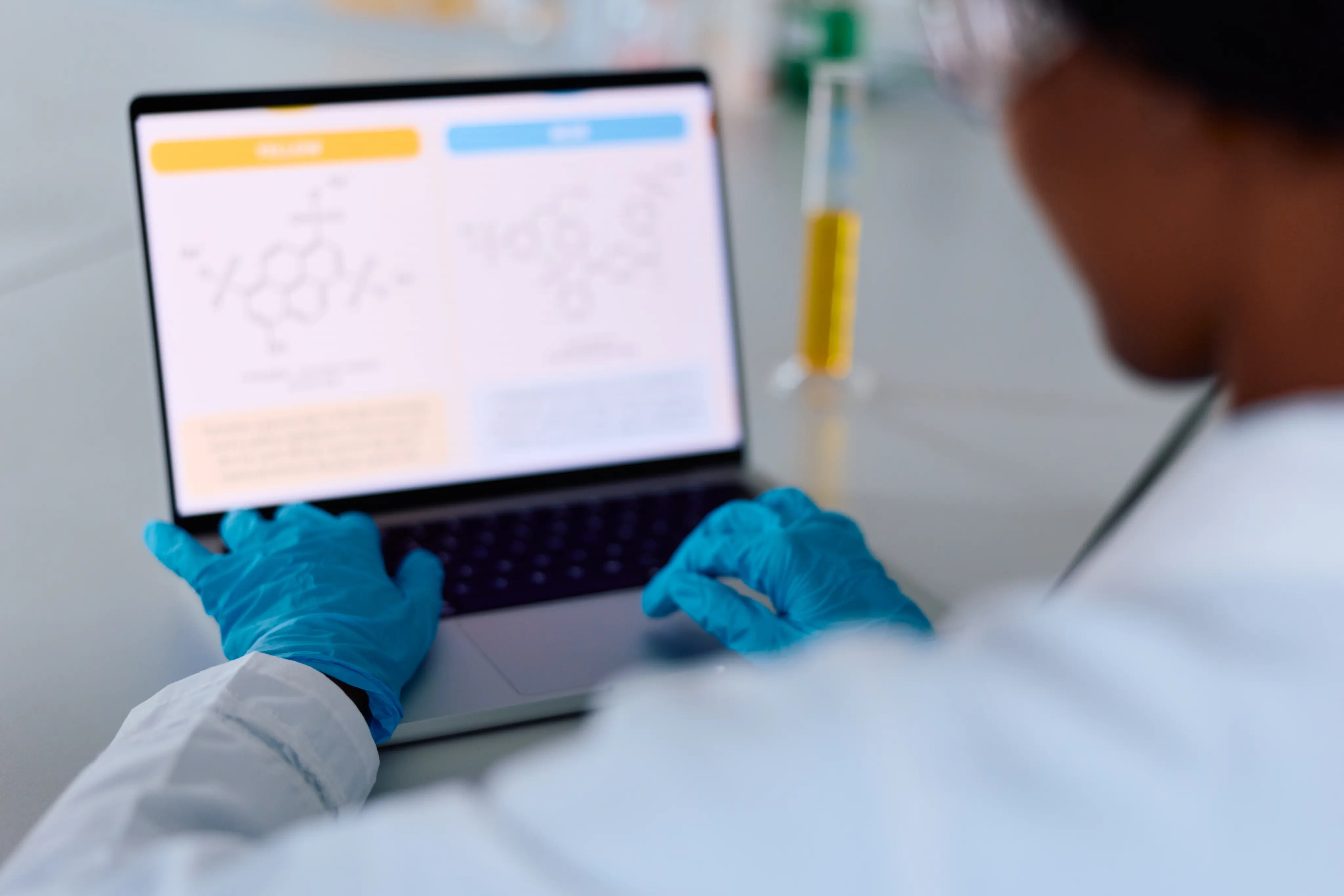 Scientist wearing gloves typing on laptop in laboratory