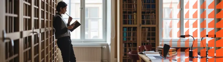 A professional standing up inside a library while reading