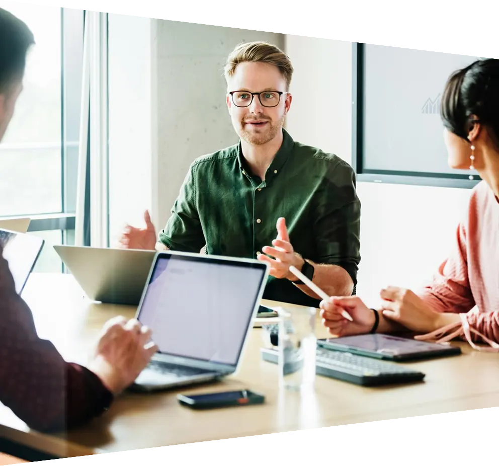  Focused team leader addressing colleagues in a meeting with a presentation in the background