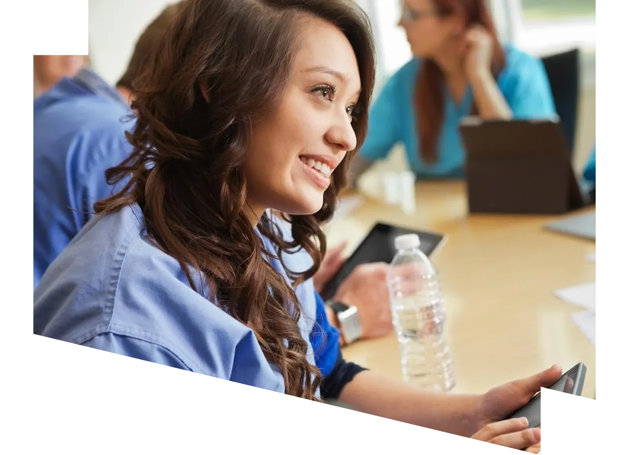 Medical professional wearing scrubs at his desk looking at digital tablet