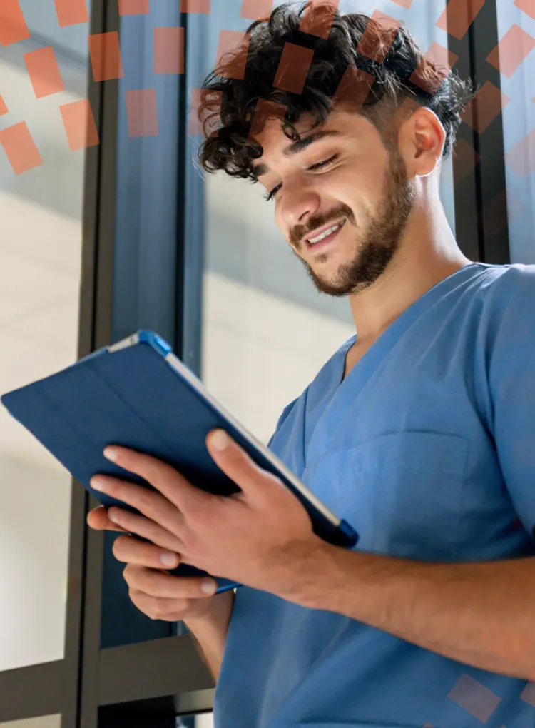 Enfermero joven sonriendo y mirando hacia abajo a una tableta