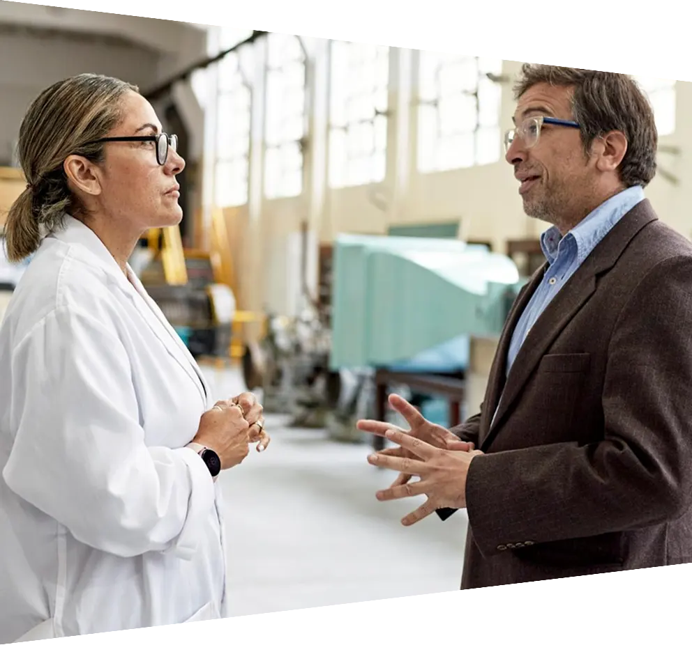 Male college professor standing face to face and conversing with woman in lab coat